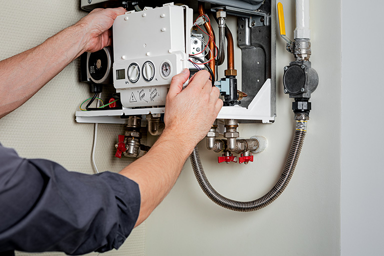 A repair person is installing a hot water boiler.