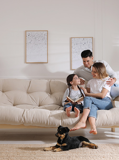 A girl reads to her mom and dad on a couch.