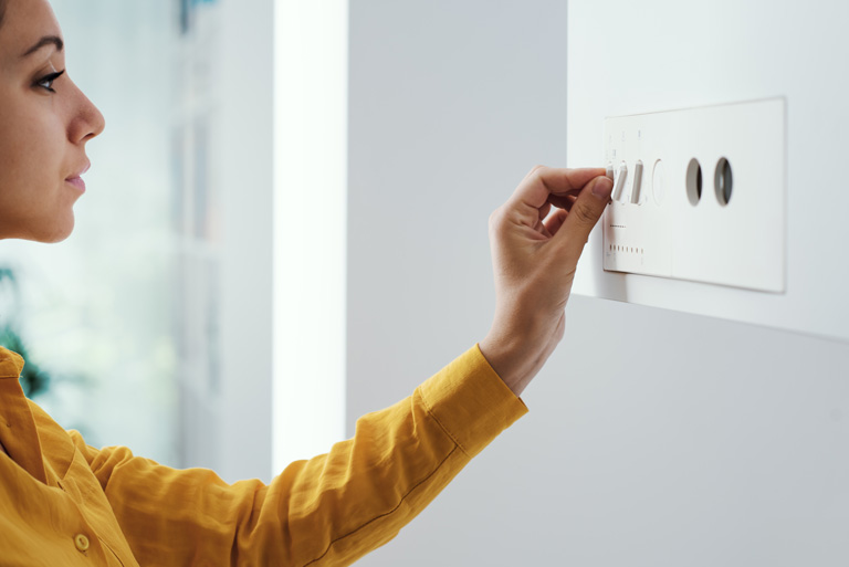 A woman adjusts a residential hot water boiler.